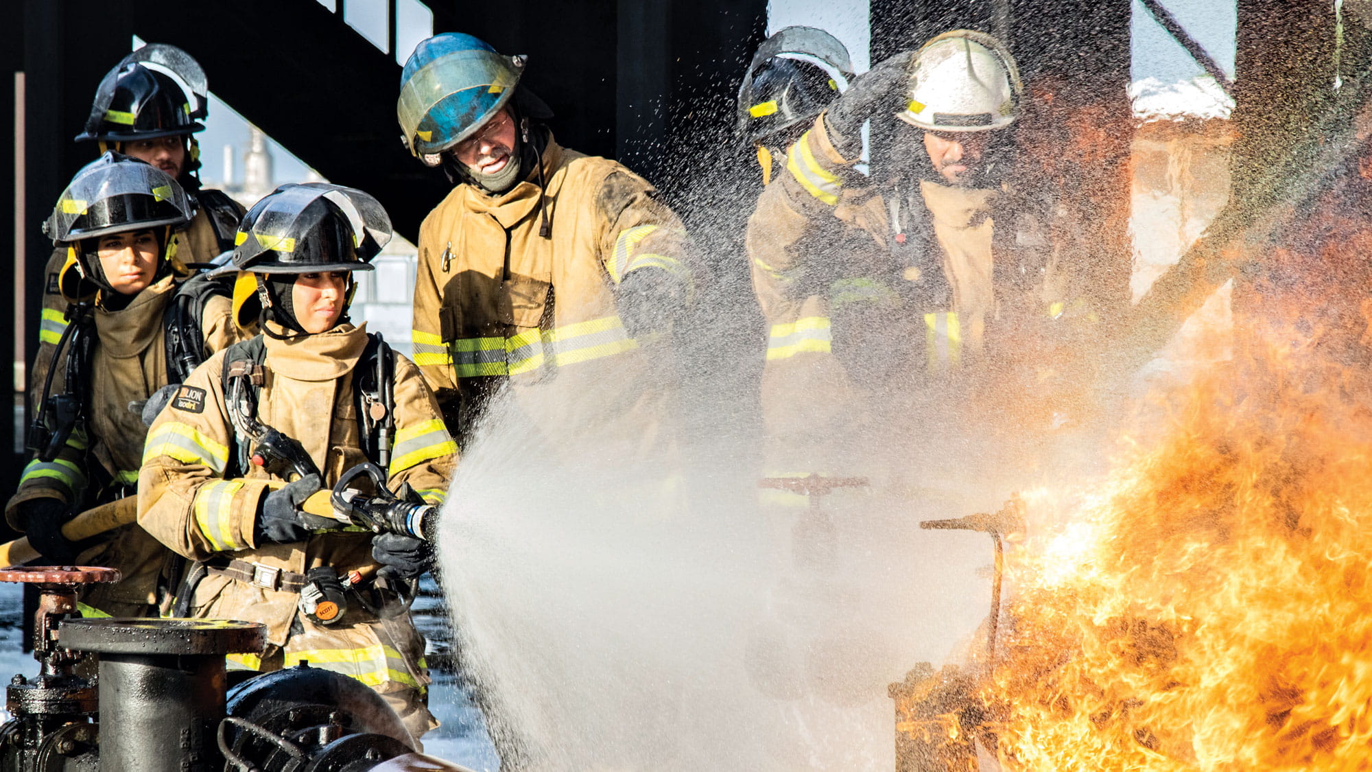 Female firefighter at Saudi Aramco fire hosing a fire